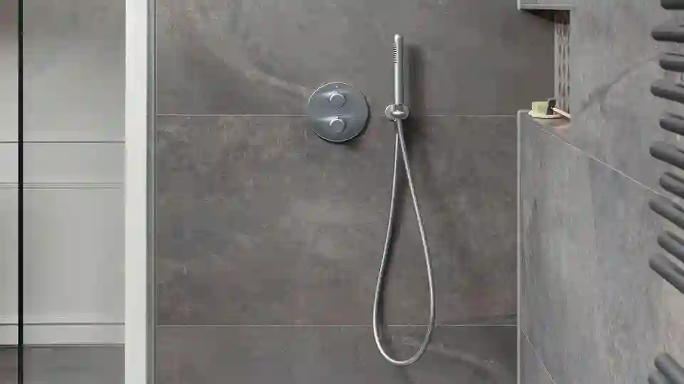 Dusche mit grauen Fliesen, unter denen sich eine nicht sichtbare Fußbodenheizung befindet.