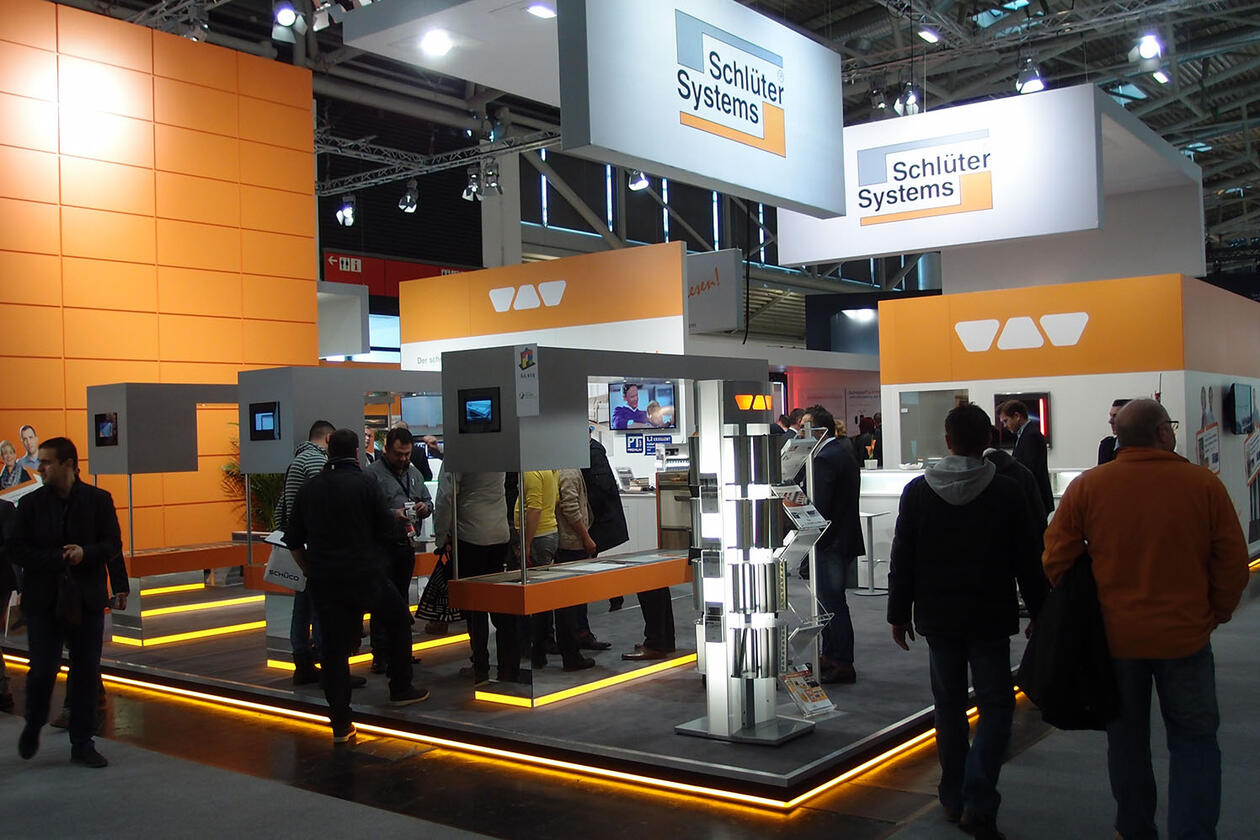 Un stand de Schlüter-Systems con diversas piezas expuestas y visitantes.