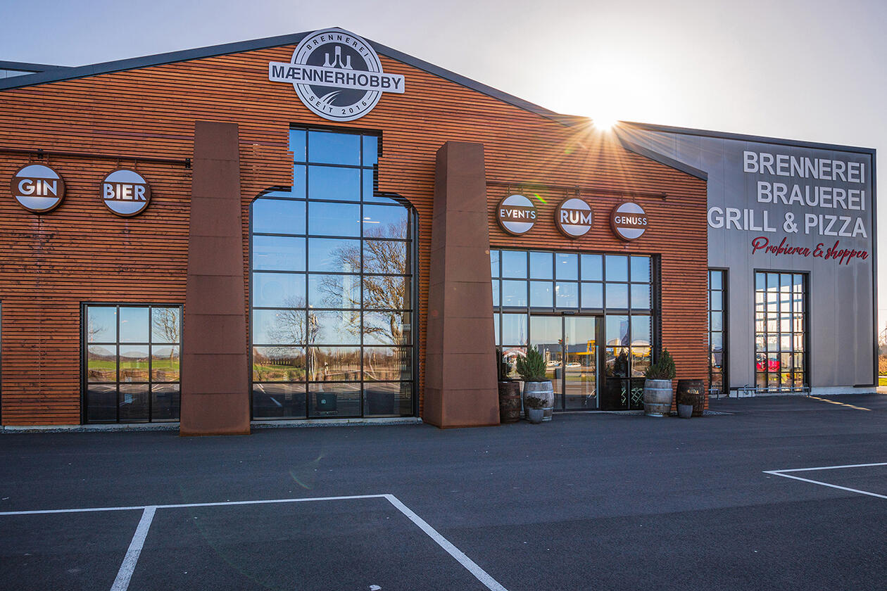 Außenansicht der Erlebnisbrennerei und -brauerei Maennerhobby mit Parkplatz