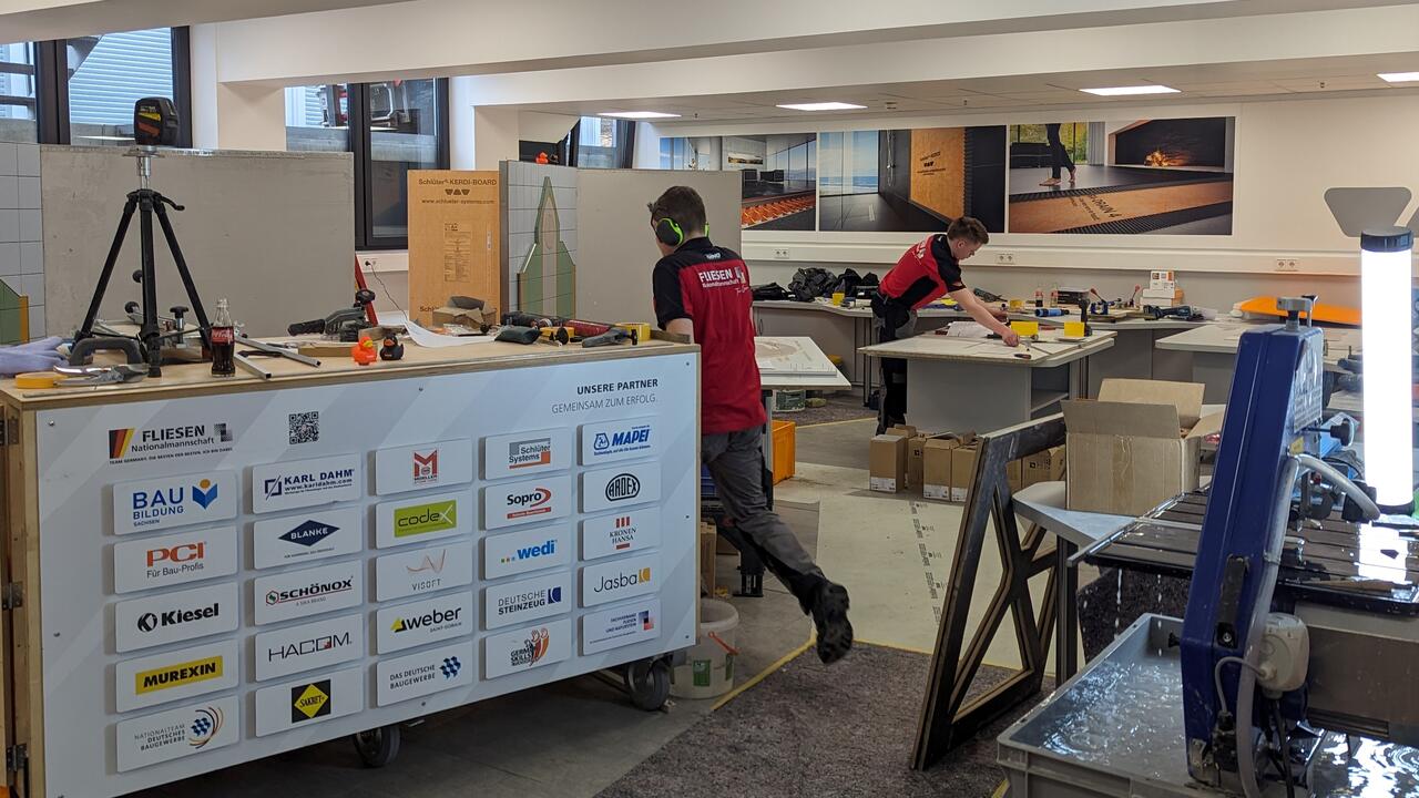 Die Fliesen-Nationalmannschaft nutzte für ihr Qualifikationstraining die Praxisräume der WorkBox. Die Fliesenlegerinnen und Fliesenleger arbeiten konzentriert in den Praxisräumen der Schlüter-WorkBox.