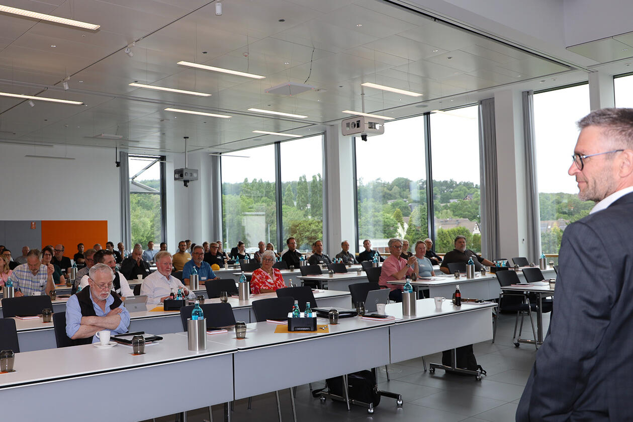 Jens Goeke von Schlüter-Systems (vorne rechts) hielt vor dem Fachpublikum einen Vortrag über BEKOTEC-THERM. Publikum sitzt an Tischreihen und hört einem Referenten zu, der rechts im Bild zu sehen ist.