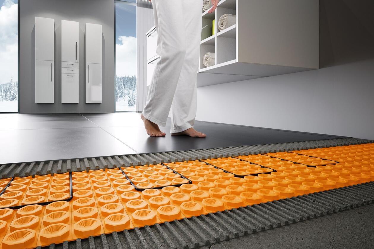 Bodenaufbau in einem Badezimmer mit elektrischer Fußbodenheizung Schlüter-DITRA-HEAT und Fliesen, auf denen eine Person barfuß läuft.
