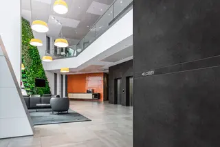 Prostor vstupu do budovy s bordurov&yacute;m profilem s potiskem na stěně, kter&yacute; ukazuje cestu do lobby.