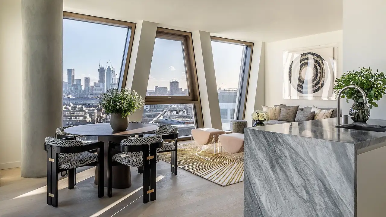 Obývací pokoj s velkými okny zaplavený světlem v jednom z apartmánů v komplexu budov The Broadway