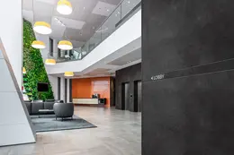 En bygnings indgangsparti med en bortprofil på væggen med tryk, som viser vej til lobby-området.