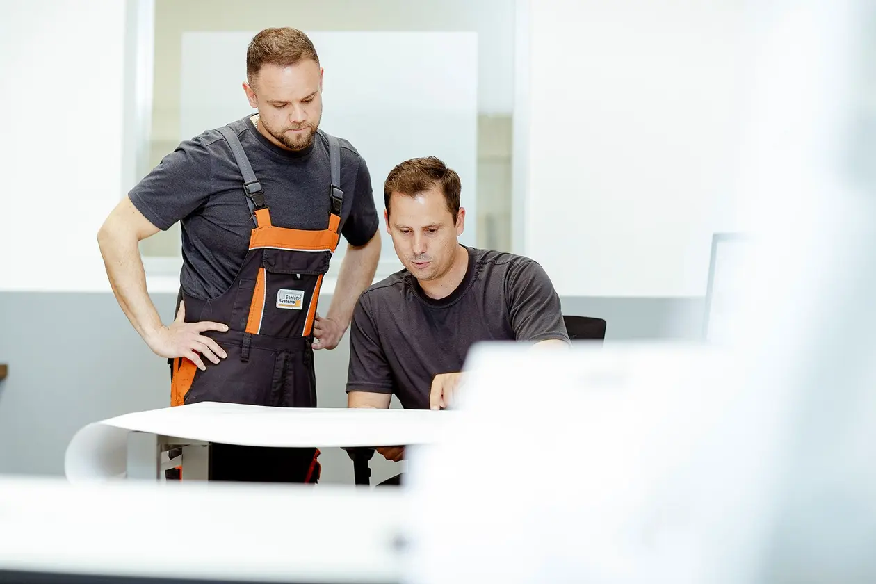Two men in work clothes at a meeting