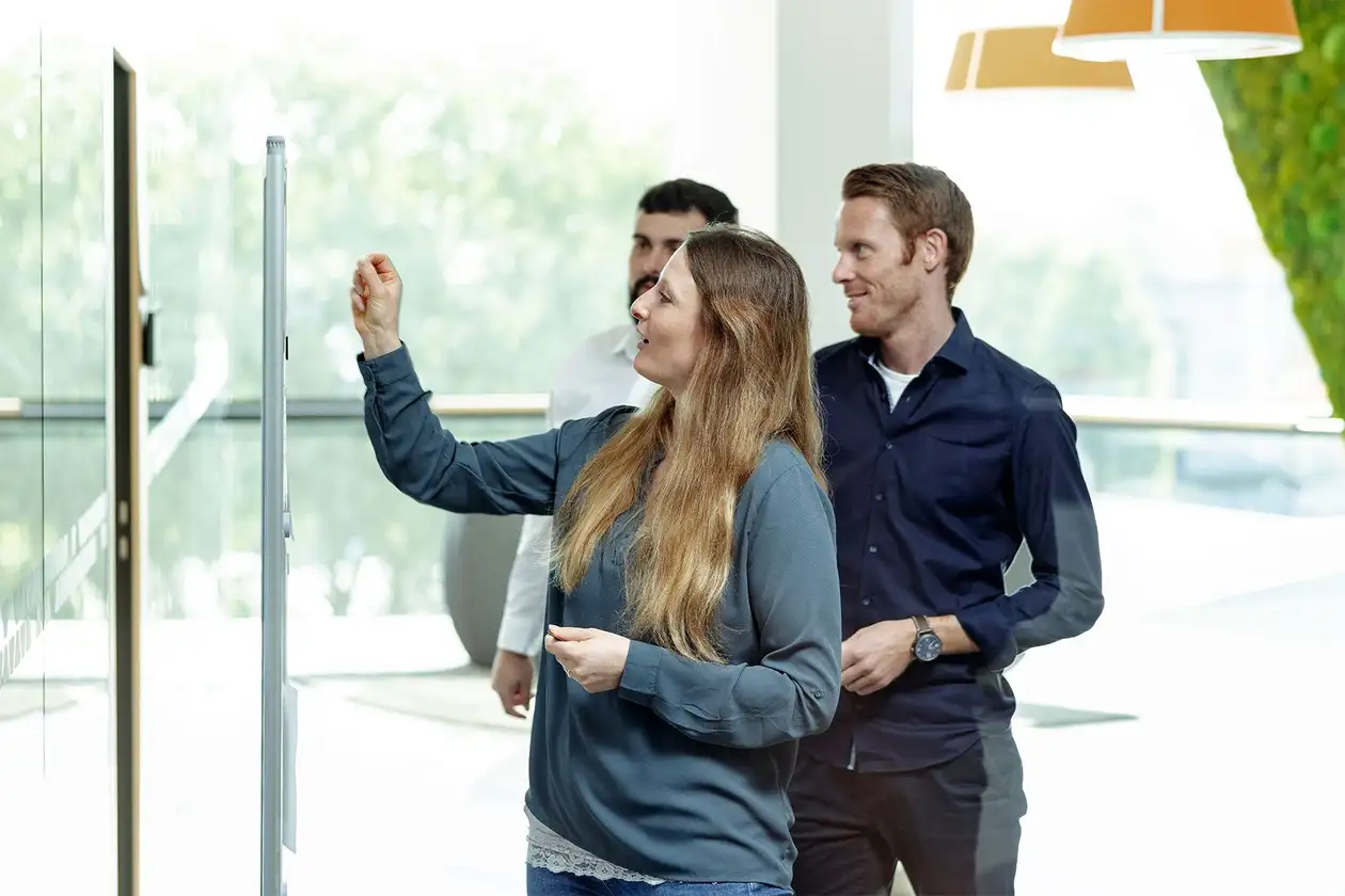 Team of two men and one woman working on a whiteboard