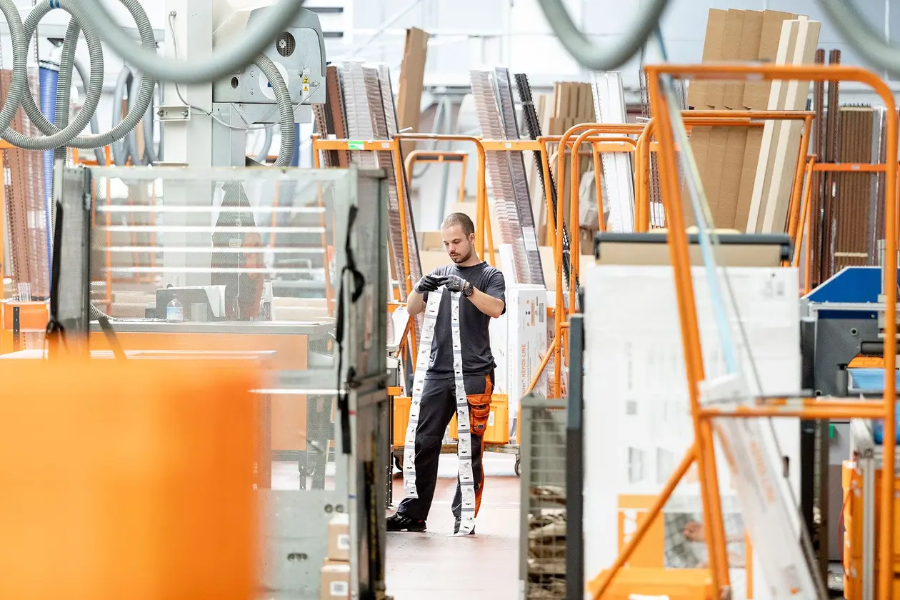 Male employee with self-adhesive packaging labels in the middle of the warehouse logistics area.