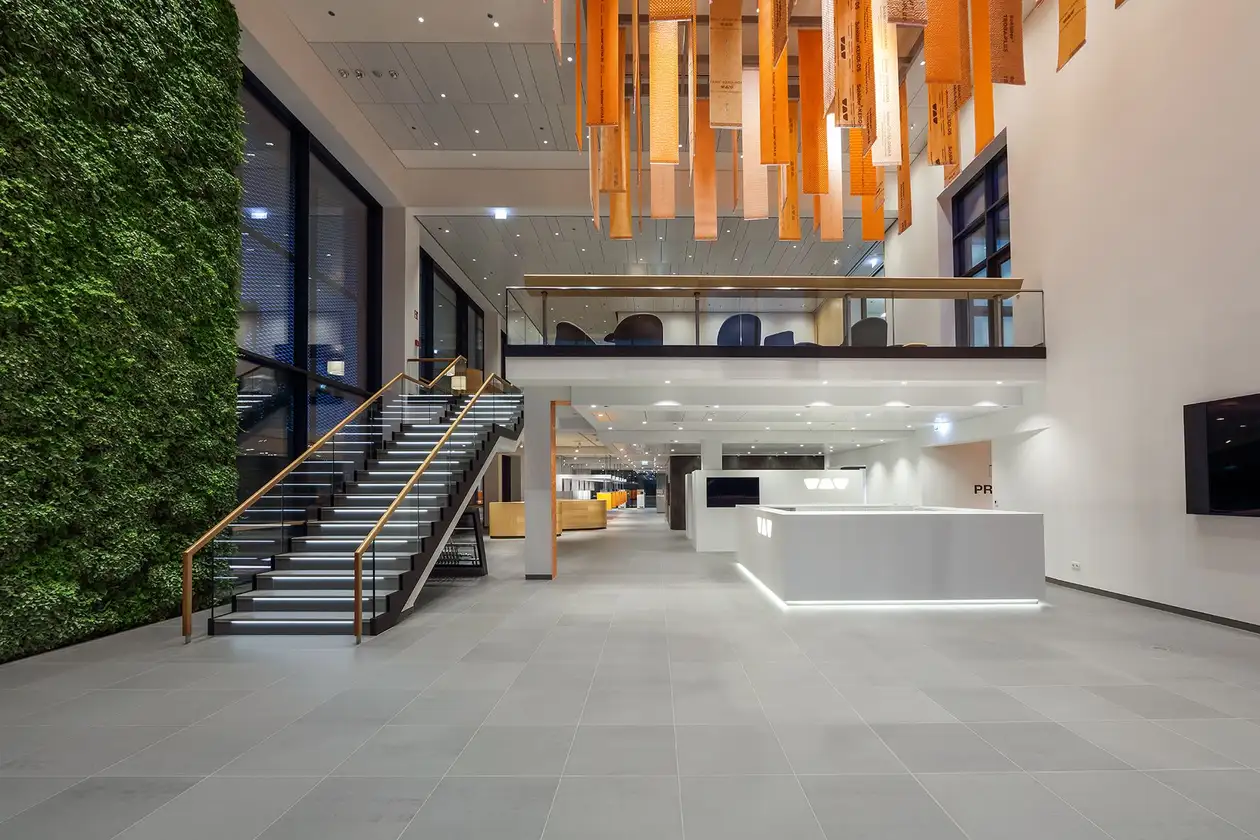 Foyer in Schlüter-WorkBox, left: planted vegetation wall, centre: wide staircase that leads to the first floor, right: reception desk