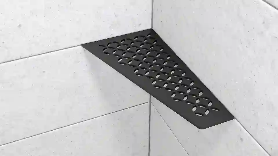 Here is a product image of the right-angled Schlüter-SHELF-E-S3 shower corner shelf in the FLORAL design and MGS matte graphite black finish, installed on light grey wall tiles