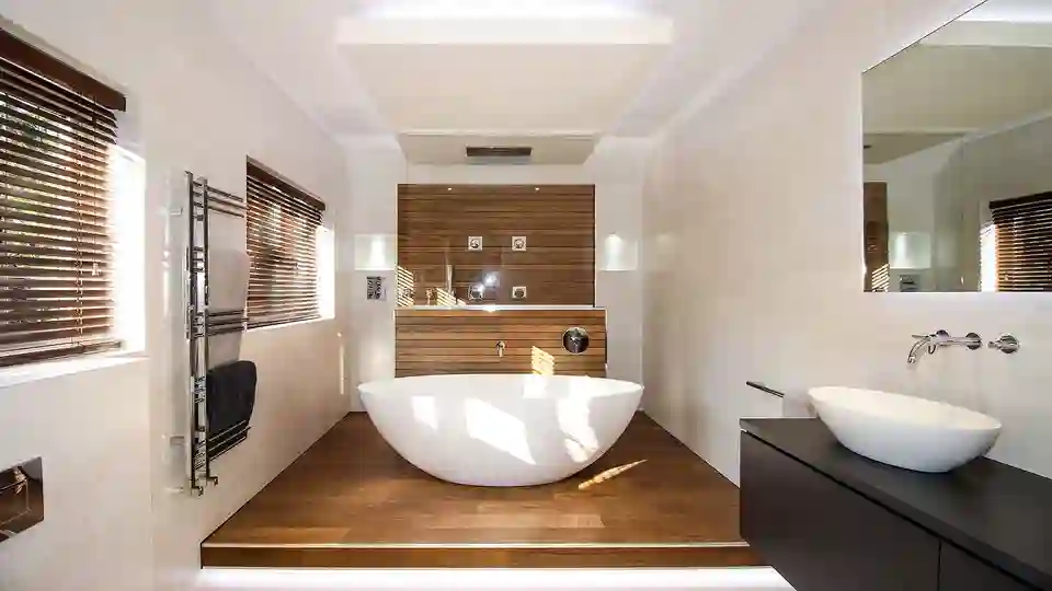 Freestanding bath surrounded with wood effect floor tiles and shower area in the background