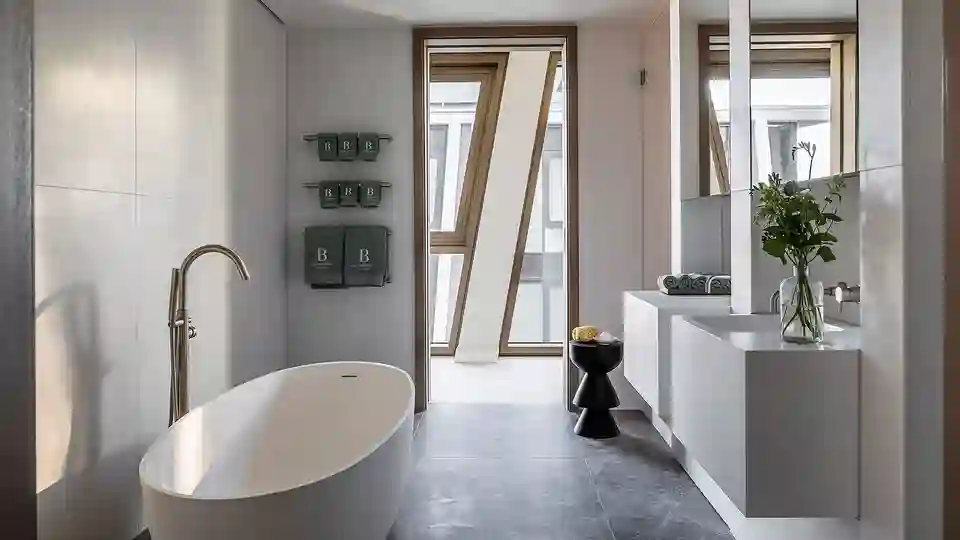 Example bathroom at The Broadway which features a freestanding bath to the left and two wall hung vanities with mirrors above on the right