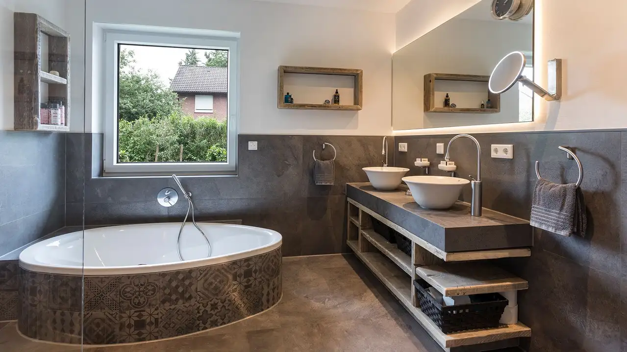 Photo of the renovated bathroom with bathtub, vanity unit and illuminated mirror.