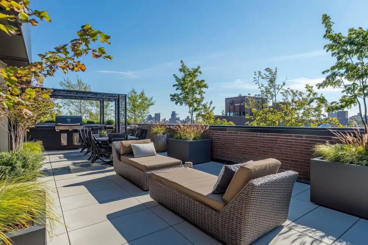 Blick auf eine gro&szlig;e m&ouml;blierte Dachterrasse unter klarem blauem Himmel mit Skyline im Hintergrund