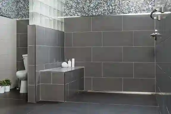 Graues, barrierefreies Badezimmer mit bodengleicher Dusche und fliesenfertiger Duschbank.