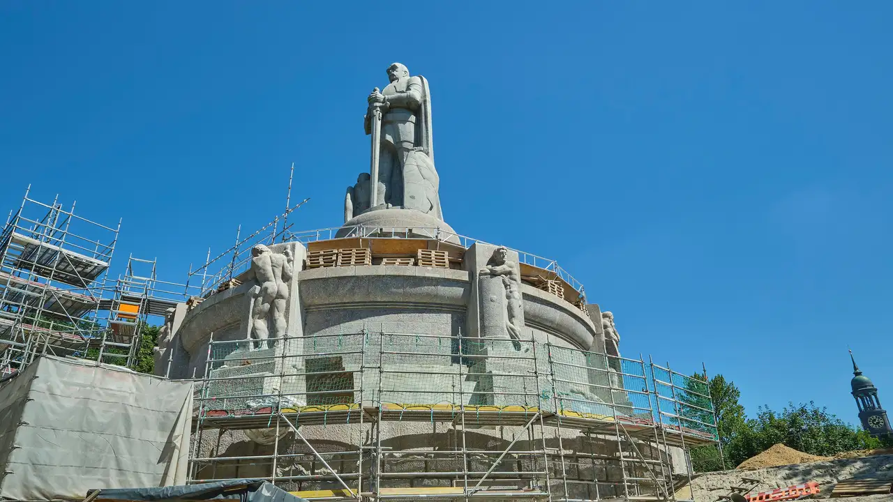 Bismarck-Denkmal umhüllt von Baugerüsten mit strahlend blauem Himmel im Hintergrund.