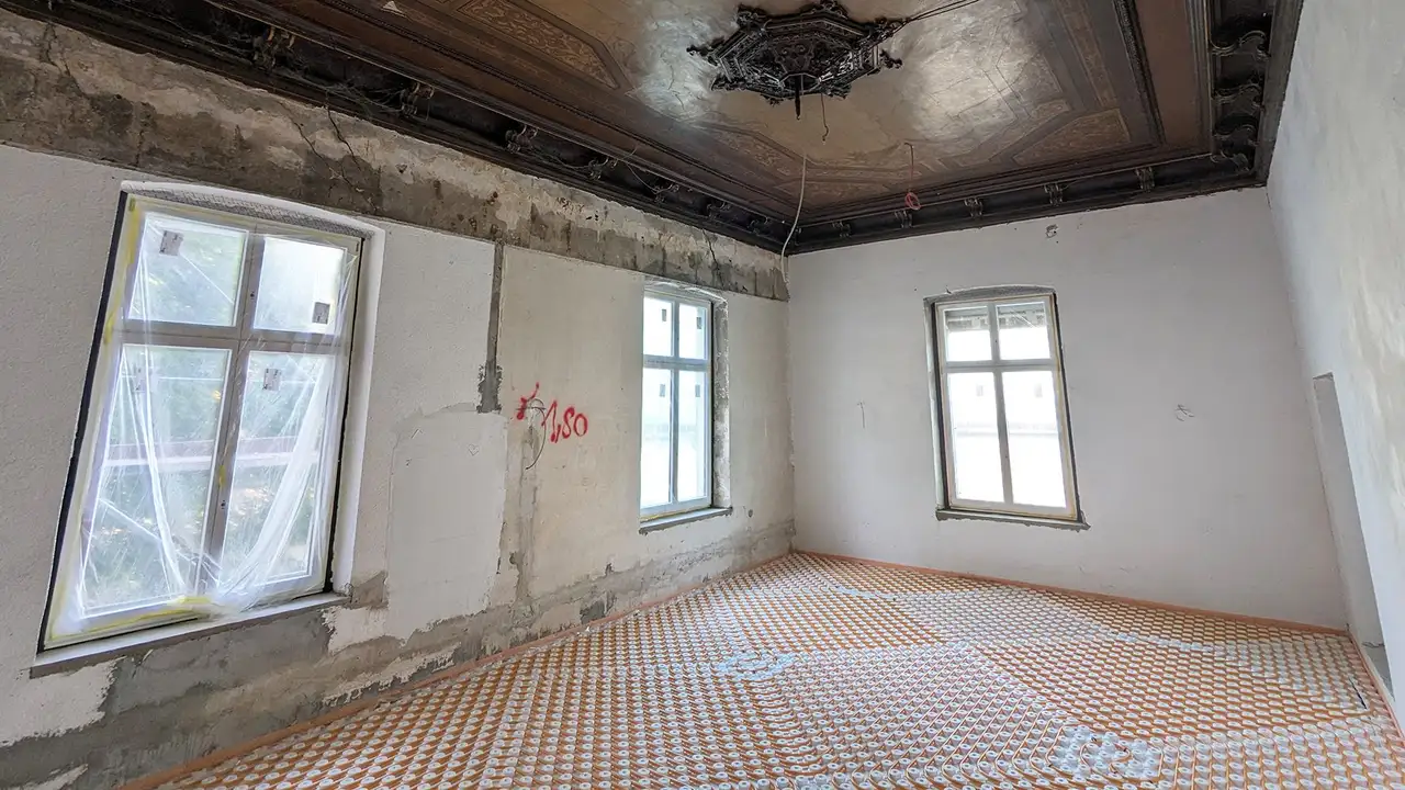 Ein Raum der Villa Cosack im Renovierungszustand mit verlegter Estrichnoppenplatte und Heizrohren auf dem Boden