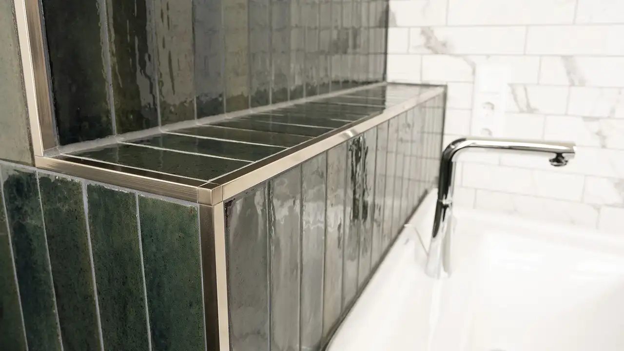 Waschbecken mit dunkelgrün gefliester Ablage und QUADEC-Abschlussprofilen in Edelstahl