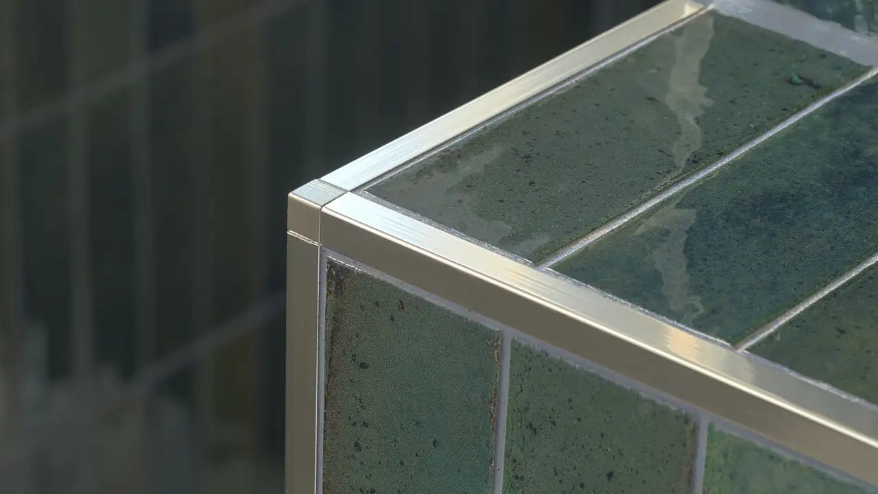 Dunkelgrün geflieste Außenecke mit QUADEC-Abschlussprofilen in Edelstahl