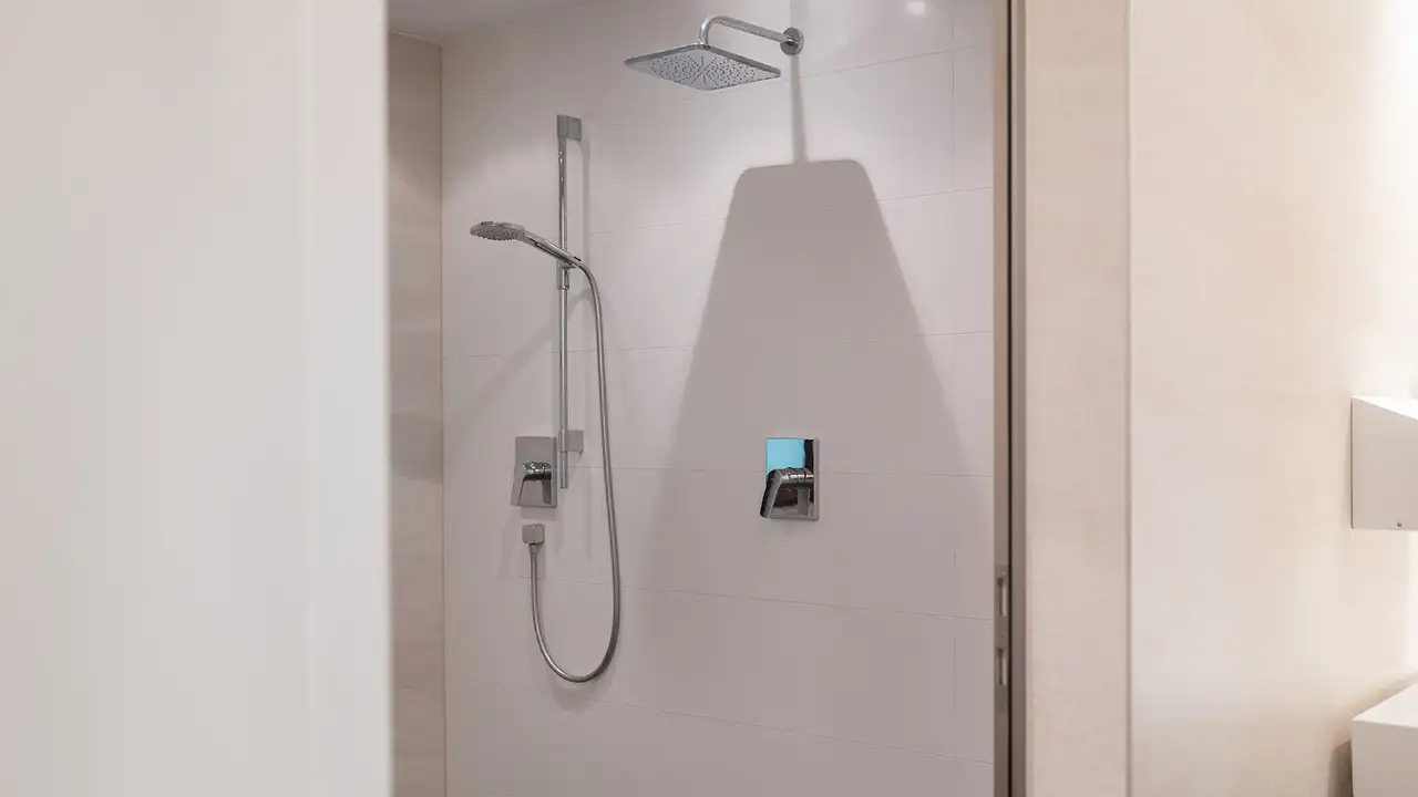 Die fertigen Duschen im Vereinsheim mit hellen Wandfliesen, Regensuche und Handbrause