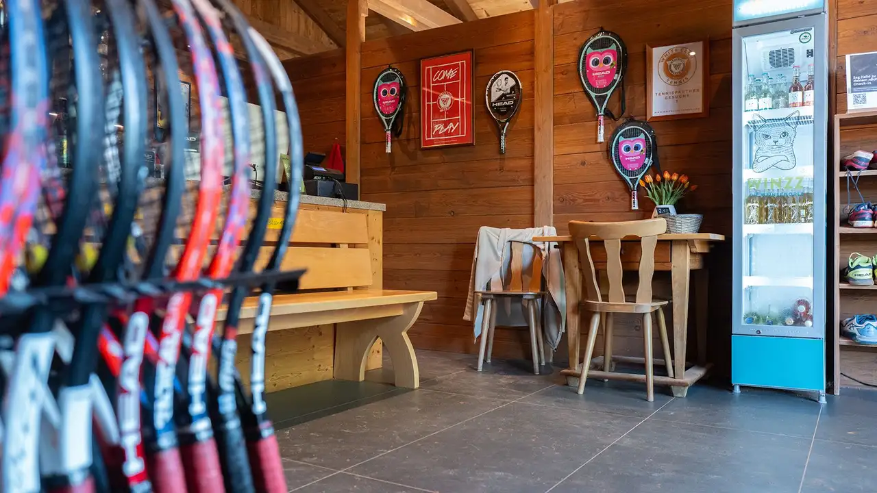 Blick in das Vereinsheim von Tennis Hirschau in M&uuml;nchen mit Bank, K&uuml;hlschrank und Tennisschl&auml;ger