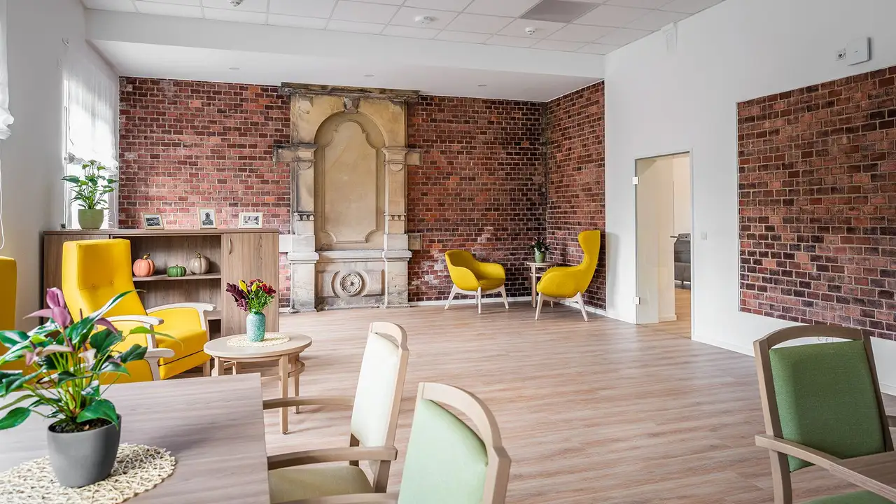 Blick in einen Gemeinschaftsraum mit historisch gemauerten Wänden und modernen, bunten Holzmöbeln