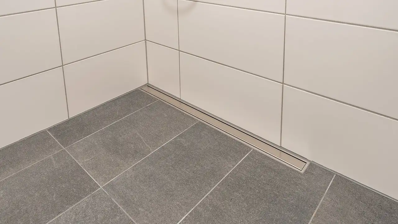 Grau gefliester Boden einer barrierefreien Dusche mit Entwässerungsrinne aus Edelstahl an der Rückwand