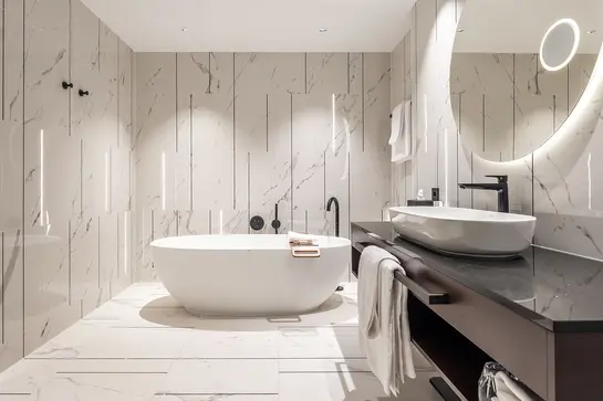 Badezimmer mit freistehender Wanne, wei&szlig;en Marmorfliesen an der Wand und beleuchteten Lichtlinien in den Fugen