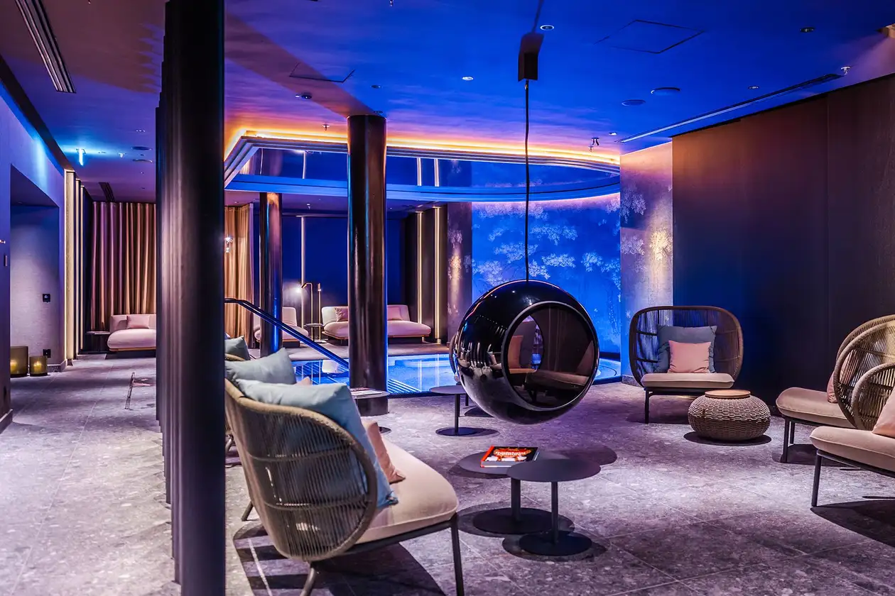 Blau beleuchteter Hotelpool mit Lounge-M&ouml;beln davor