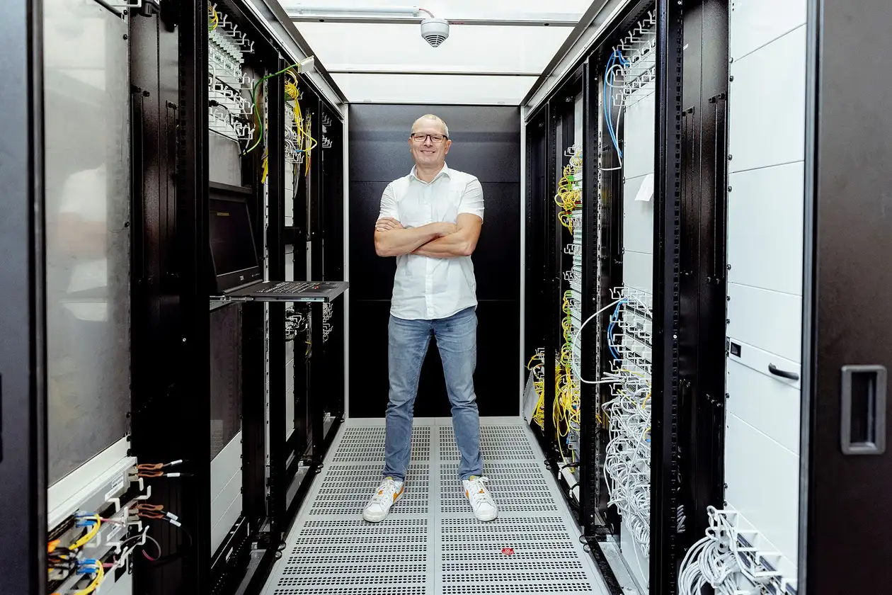Männlicher Mitarbeiter aus IT steht zwischen Servern des Rechenzentrums von Schlüter-Systems.