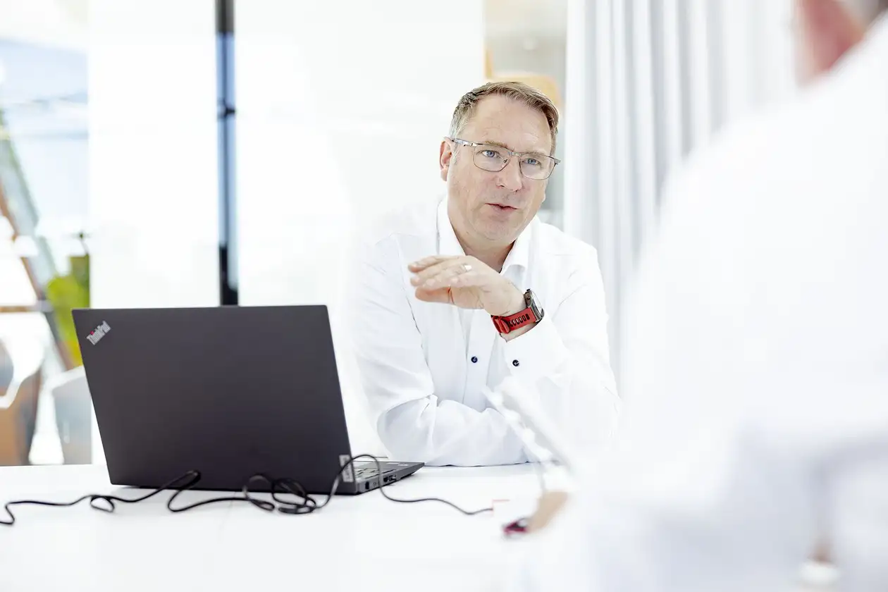 Zwei männliche Kollegen sitzen sich im Gespräch gegenüber.