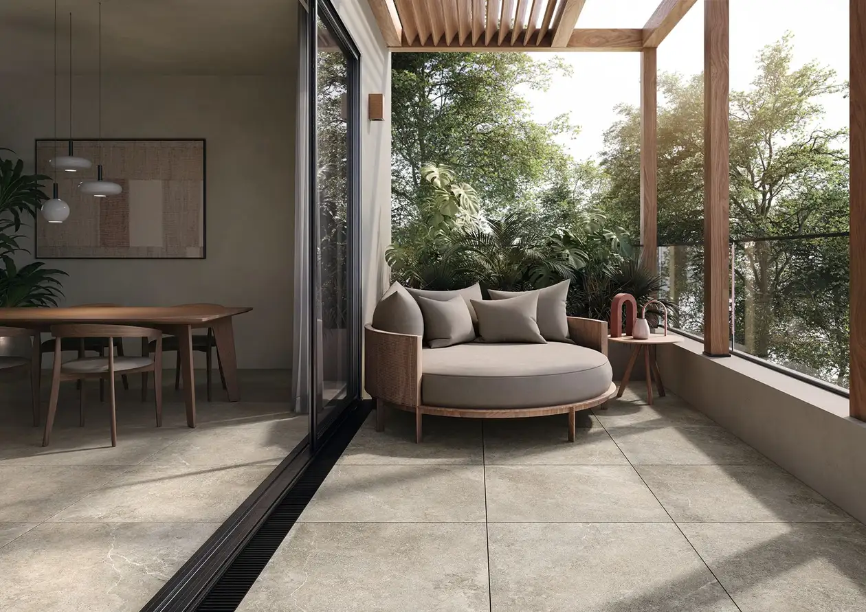 Grau gefliester Balkon mit gem&uuml;tlicher Sitzecke aus Lounge-M&ouml;beln im Hintergrund