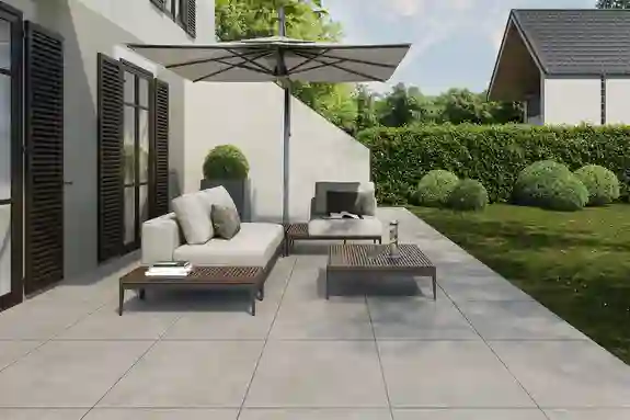 Helle Terrasse,  mit zwei Stühlen, einem Tisch, einem Sonnenschirm und einem Blick ins Grüne.