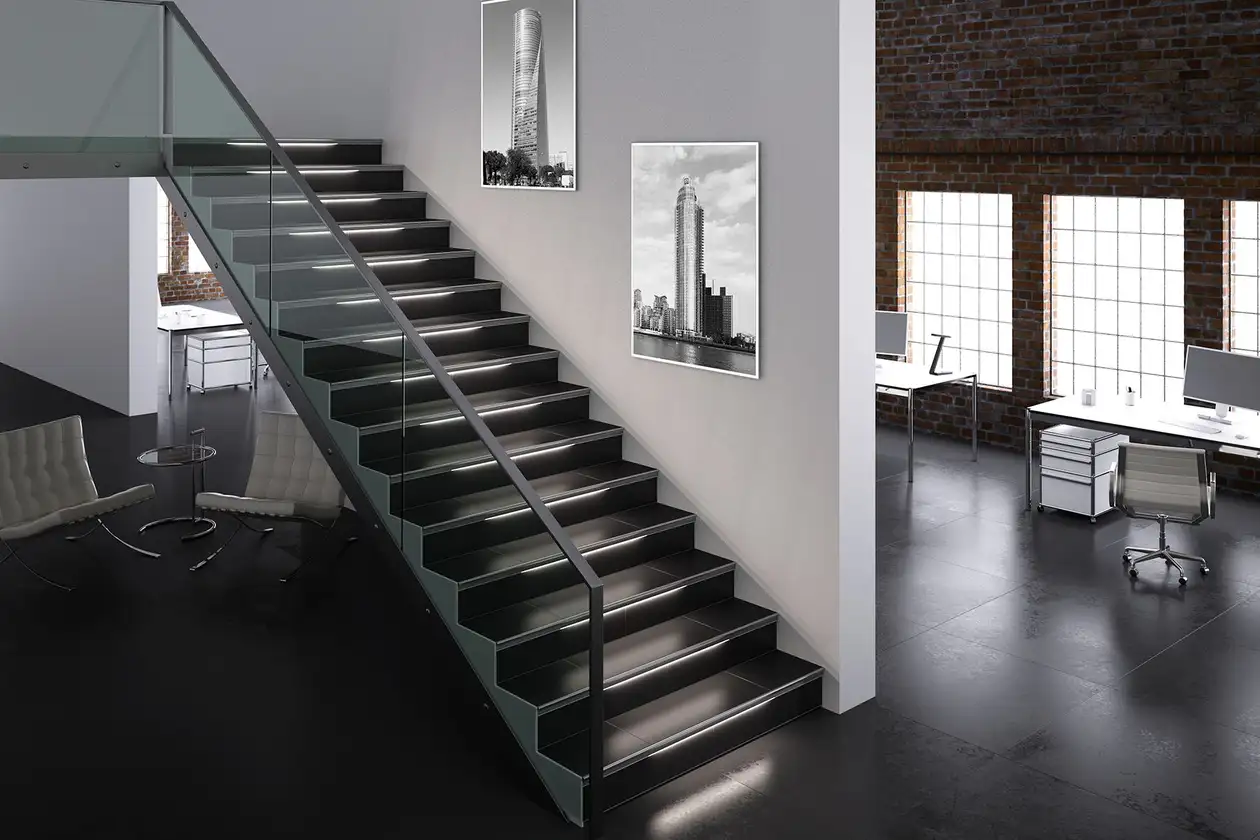Mit einer Glaswand versehene, dunkel geflieste Treppe in einem Loft, die Treppenkanten sind beleuchtet