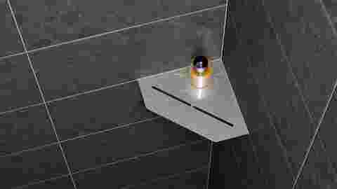 Nahansicht einer Duscheckablage Schlüter-SHELF-E-S2 im Design PURE an dunkelgrau gefliesten Wänden