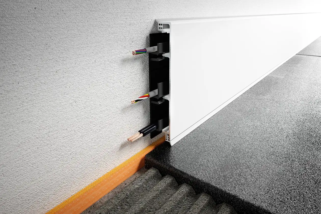 Nahaufnahme eines Sockelprofils mit integrierten Kabelkanälen und darin verlegten Kabeln