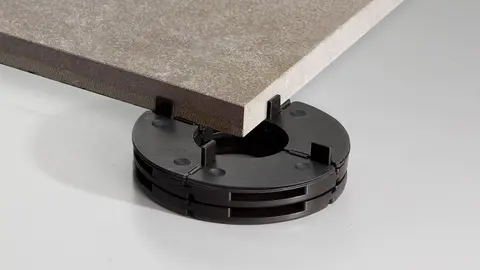 Eine hellbraune Terrassenplatte liegt auf einem schwarzen TROBA-LEVEL-PL 10 Plattenlager