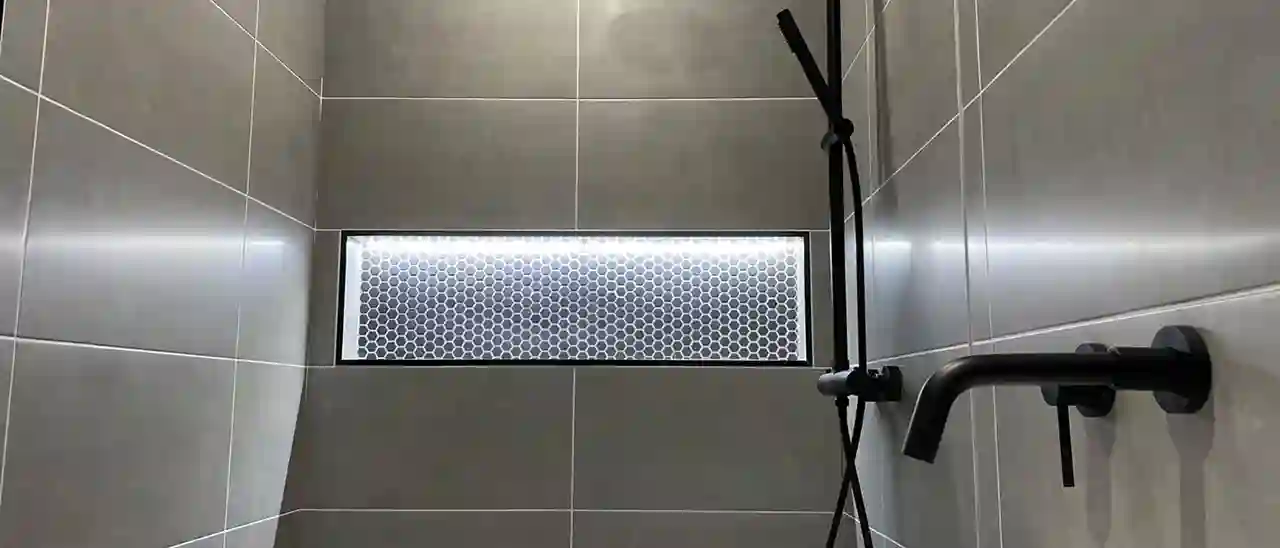 Graues Badezimmer mit schwarzen Akzenten und beleuchteter Nische Schlüter-KERDI-BOARD-NLT.