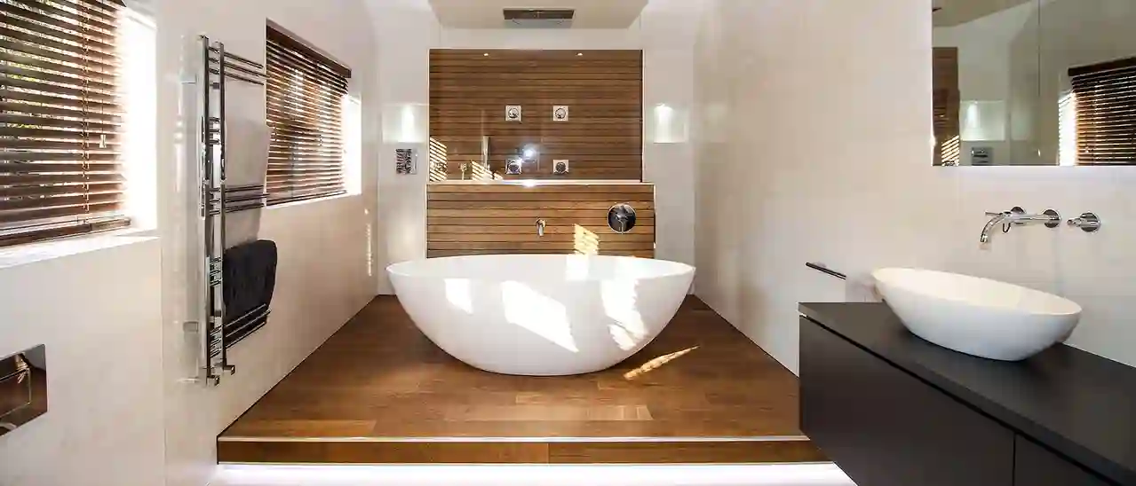 Freistehende Badewanne, umgeben von Bodenfliesen in Holzoptik und einem Duschbereich im Hintergrund.