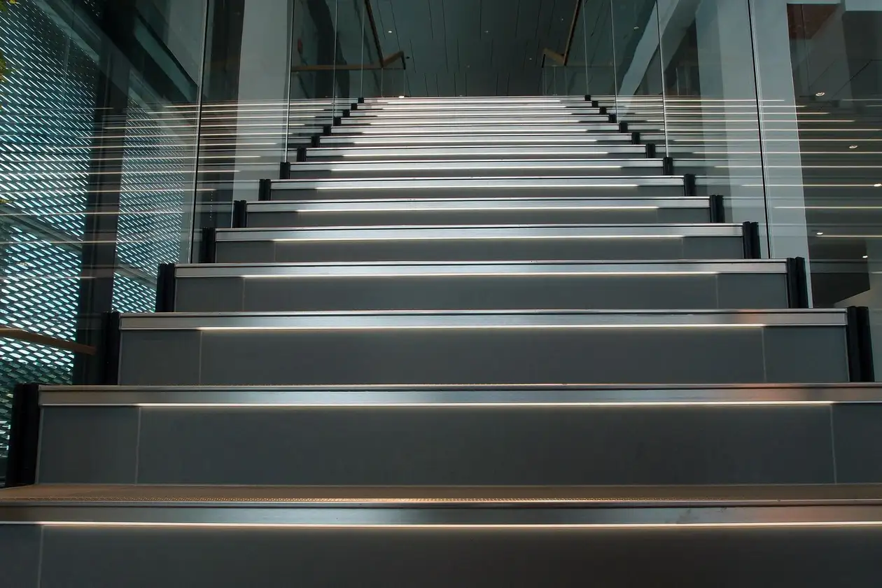 Close-up auf eine breite beleuchtete Treppe mit Fokus auf den grau gefliesten Stufen