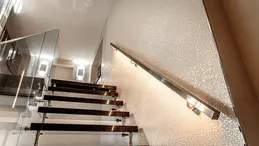 Freischwebende Treppe mit Glasgel&auml;nder auf der linken und beleuchtetem Handlauf auf der rechten Seite.
