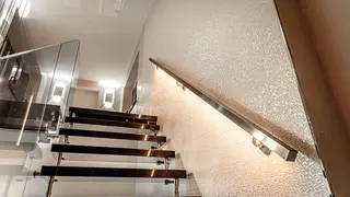 Freischwebende Treppe mit Glasgel&auml;nder auf der linken und beleuchtetem Handlauf auf der rechten Seite.