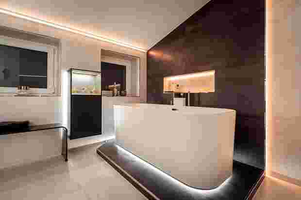 Badezimmer mit dunklen Akzenten, freistehender Badewanne und Schlüter-Lichtprofilen.
