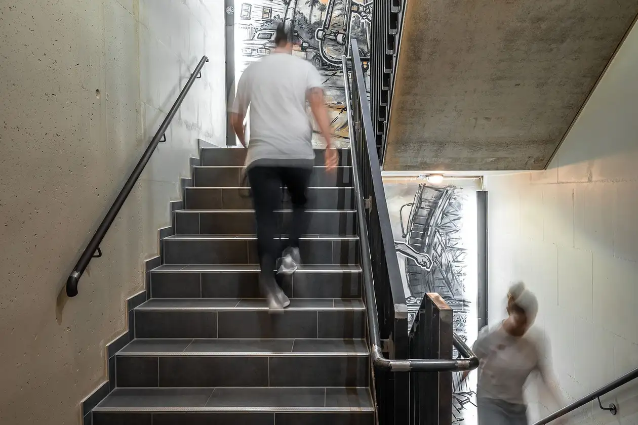 Mann und Frau gehen hintereinander eine Treppe in einem bunt gestalteten Hotel-Treppenhaus hinauf