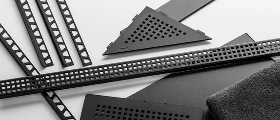 Selección de productos de Schlüter-Systems en negro mate MGS (pueden verse, entre otros, los perfiles de cantonera JOLLY, QUADEC y RONDEC, el desagüe lineal de plato de ducha KERDI-LINE y el estante de diseño SHELF)