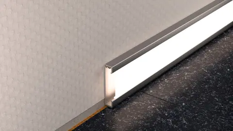 Perfil Schlüter-DESIGNBASE-QD con iluminación en blanco cálido como zócalo para el recubrimiento del suelo