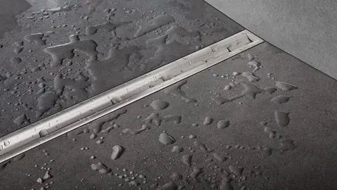 Caniveau d'écoulement d'une douche avec Schlüter-KERDI-LINE-VARIO en design Cove et avec finition TRENDLINE grise