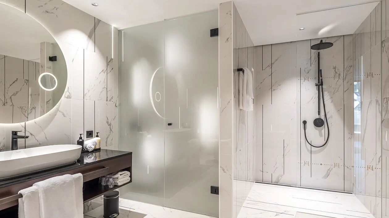 Salle de bains moderne avec carrelage en marbre blanc, technique d'&eacute;clairage et douche &agrave; l’italienne