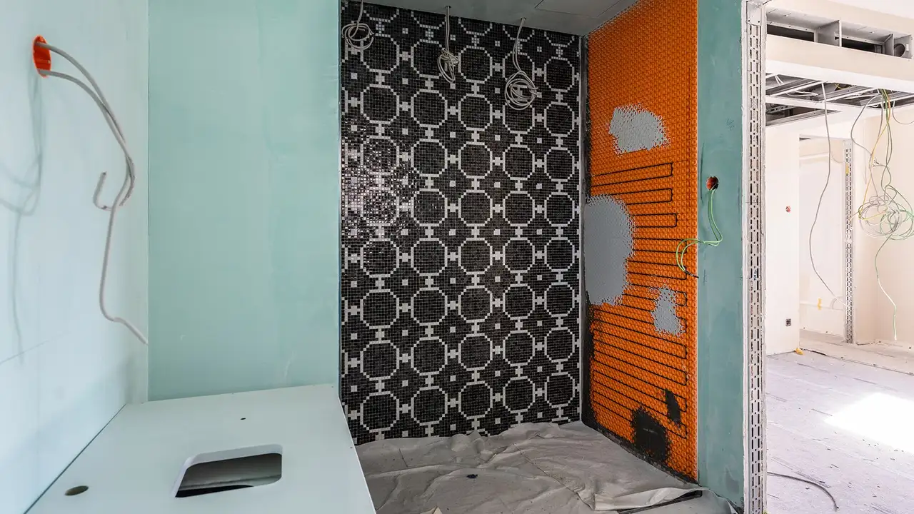 Salle de bains en cours de r&eacute;novation dans la partie historique de l’h&ocirc;tel, avec un syst&egrave;me de chauffage DITRA-HEAT-E sur la paroi droite de la douche