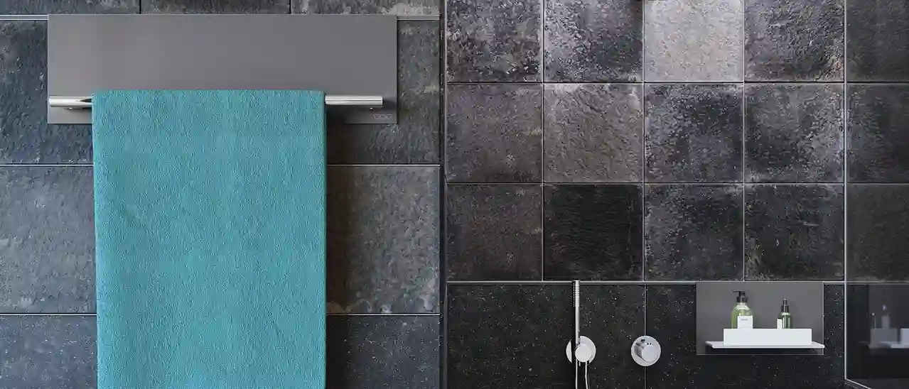 Une salle de bains avec revêtement carrelé de couleur sombre et porte-serviettes gris de la gamme Schlüter-ARCLINE.